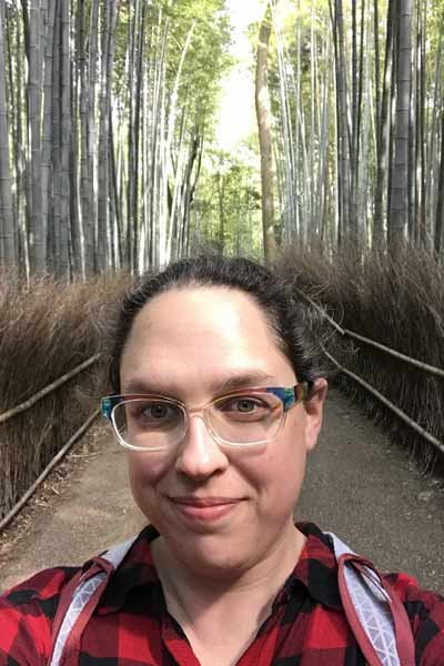 An informal portrait of Meredith Power on a (walking) bridge, in the woods