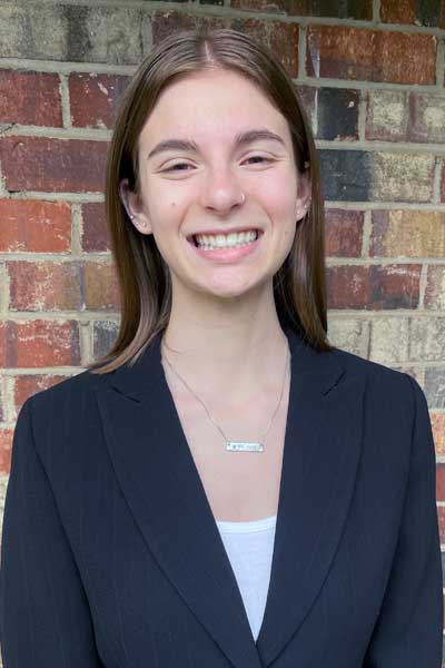 A young woman standing outside in front of a brick wall