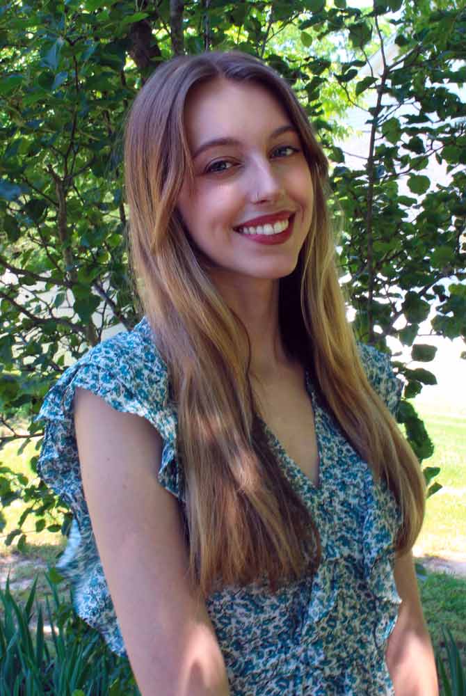 A three quarters informal portrait of a young lady outside in a garden