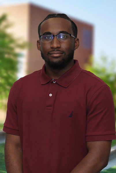 A young man standing outside in a courtyard on campus