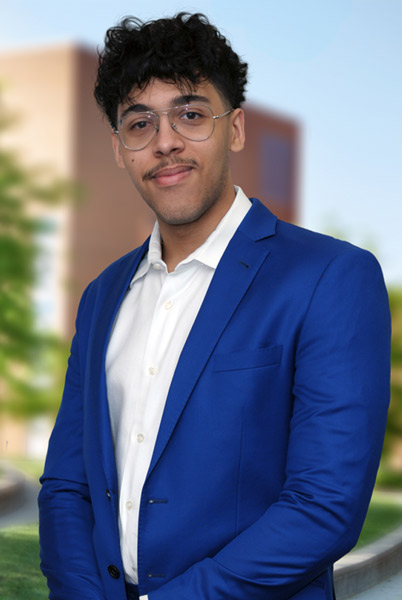 A young man standing outside in a courtyard on campus