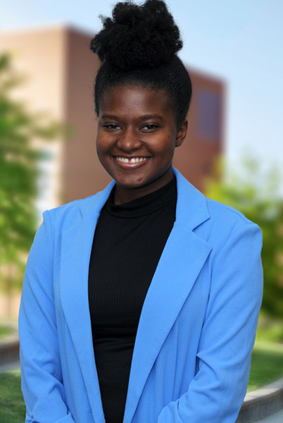 A young woman smiling while standing alone outside in a courtyard on campus