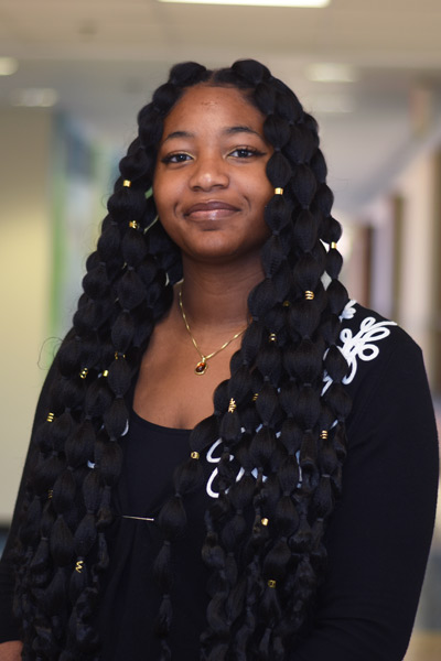 A three quarter portrait of a smiling Yonu standing in a hallway