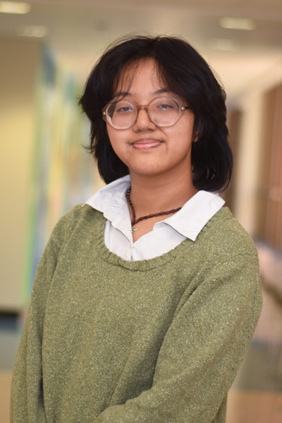 A three quarter portrait of a smiling Diane standing in a hallway